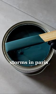 someone is painting the floor with blue paint and a wooden spatula in their hand