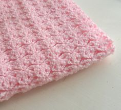 a pink crocheted blanket sitting on top of a table