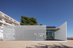 the entrance to an office building with white perfored panels on it's sides