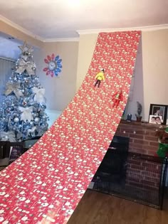 a man on a snowboard going down the side of a ramp in front of a christmas tree