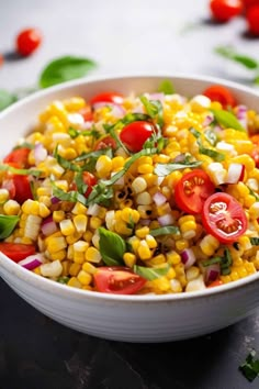 a white bowl filled with corn, tomatoes and green garnish on top of a table