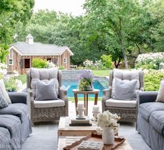 a living room with couches and chairs in front of a swimming pool, surrounded by trees