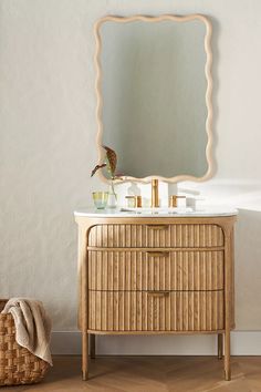 a white sink sitting under a mirror next to a wooden dresser