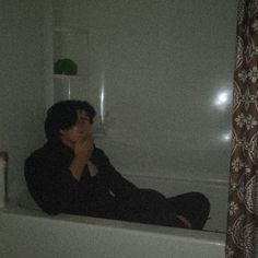 a man sitting in a bathtub with his hand on his face