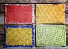 four quilted placemats sitting on top of a wooden table