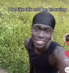 a man in black shirt and headband standing in grass with an instagramtion on his face