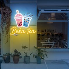 a neon sign that says boba tea in front of a window with potted plants