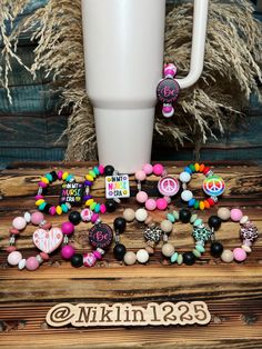 a wooden table topped with lots of different types of beads and buttons next to a white cup