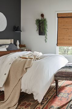 a bed with white linens and blankets in a bedroom next to a large window