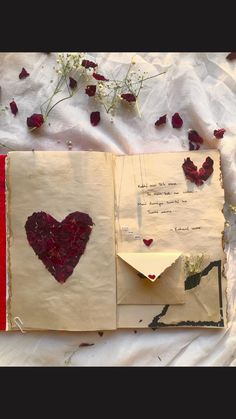 an open book with paper hearts and flowers on the pages, next to it is a poem written in cursive writing