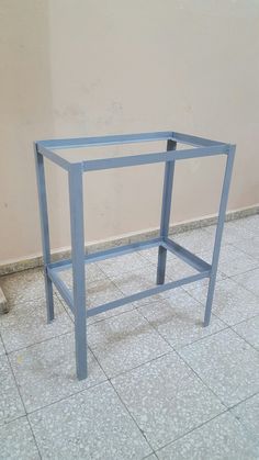 a blue metal table sitting on top of a tile floor next to a wall and a white tiled floor