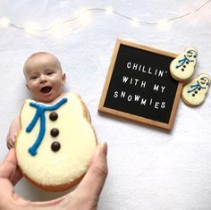 a person holding a cupcake in front of a small sign that says chillin'with my snowmies