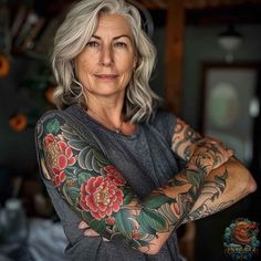 an older woman with grey hair and tattoos on her arms is looking at the camera