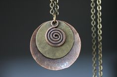 "This necklace is made with antique copper disc that I hammered first, then to give more texture and character, I domed them. I added some brass discs hand hammered as well and some antique copper swirl charms. Finish : Antique copper ( 32mm ) discs, antique brass discs round and antique copper swirl charm Matching Earrings : https://www.etsy.com/listing/478701638/boho-earrings-bohemian-earrings-copper?click_key=6dad1df60f95c805e69ff3bcc39ff945fde710ab%3A478701638&click_sum=8a24f627&ref=shop_hom Bronze Hammered Bohemian Necklace, Hammered Bronze Copper Necklace, Bronze Hammered Copper Necklace, Bohemian Copper Pendant Necklace, Bohemian Copper Oval Pendant Jewelry, Bohemian Brass Necklace With Patina, One-of-a-kind Copper Round Pendant Jewelry, Bohemian Coin-shaped Metal Necklace, Boho Pendant Necklace