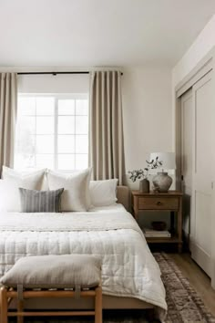 a white bed sitting in a bedroom next to a window