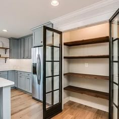 an empty kitchen with open shelving in the center and wood floors on both sides