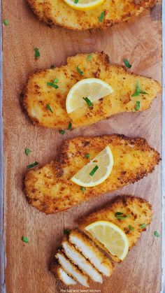 three pieces of chicken with lemon wedges on a cutting board