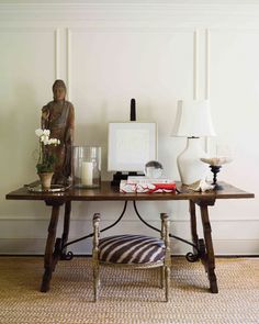 a wooden table topped with a lamp next to a statue