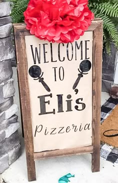 a sign that says welcome to eli's pizzaria with a red flower on top