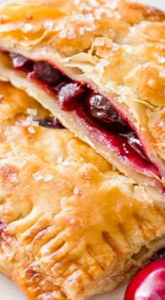 two cranberry turnovers on a white plate next to an orange and red apple