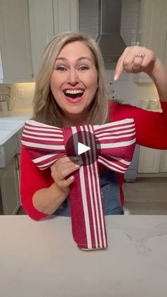 a woman holding up a red and white striped bow