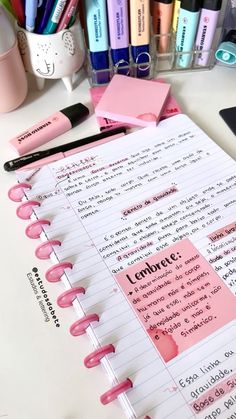 an open notebook with notes and pens on it