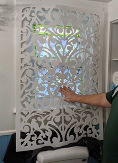 a man standing next to a white wall with cut out designs on it's side