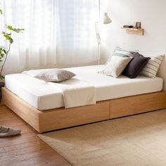 a bed sitting on top of a wooden floor next to a window