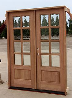 a man standing in front of a wooden double door with mirrors on the doors side