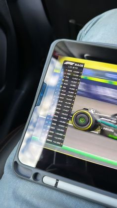 a person holding a tablet in their hand with a race car on it's screen