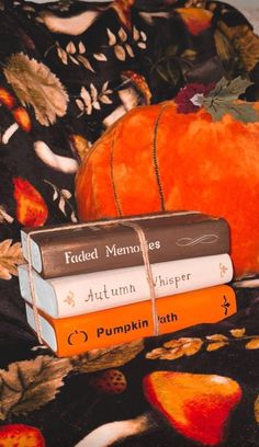 two books stacked on top of each other next to an orange pumpkin and black background