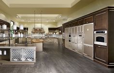 a large kitchen with lots of counter space and appliances on the walls, along with wooden flooring