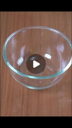 a clear glass bowl on a wooden table with a black circle in the center and white circles at the bottom