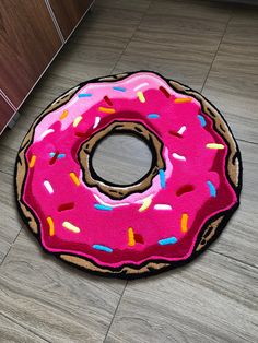 a pink donut with sprinkles is on the floor next to a cabinet