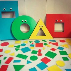 three wooden letters with faces and shapes on the floor next to each other in front of a white wall