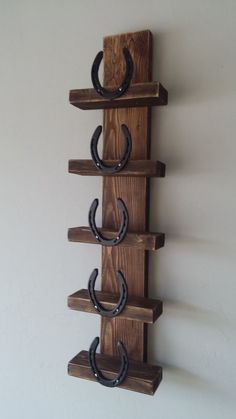 a wooden shelf with three horseshoes mounted to it's sides and two hooks on each side