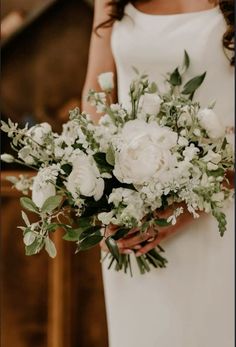 a bride holding a bouquet of white flowers