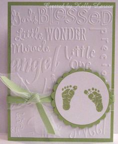 a card with a baby's footprints on it and a green ribbon around the edge