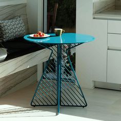 a blue table sitting on top of a white floor next to a window sill