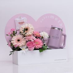 pink and white flowers are in a box with a coffee mug next to it that says happy mother's day