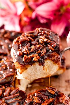 a close up of a doughnut with pecans on it and chocolate sauce drizzled over the top