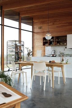 an open kitchen and dining room with wood paneling on the walls, floor to ceiling windows