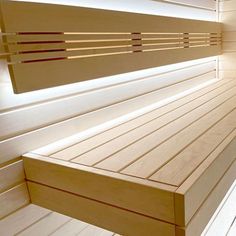 a wooden bench sitting in the middle of a room with white walls and wood flooring