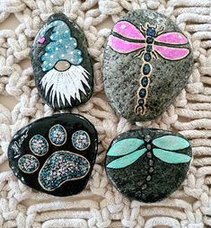 four painted rocks with dragonflys on them sitting on top of a blanket next to a crochet afghan