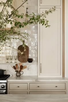 a kitchen with white cupboards and an oven in the center, surrounded by greenery