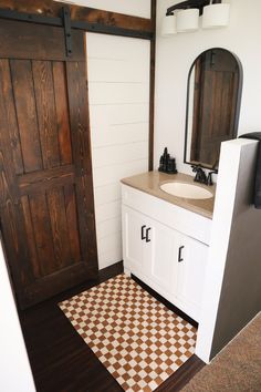 a bathroom with a sink, mirror and wooden door