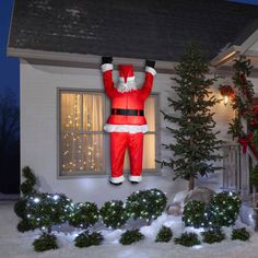 an inflatable santa clause standing on top of a house