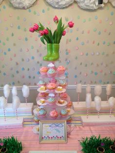 a table with cupcakes and pink flowers in a vase on top of it