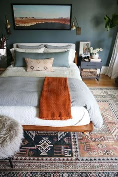 a bedroom with blue walls and an orange throw blanket on the bed in front of it