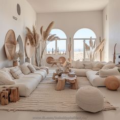 a living room filled with white furniture and lots of natural decor on top of it